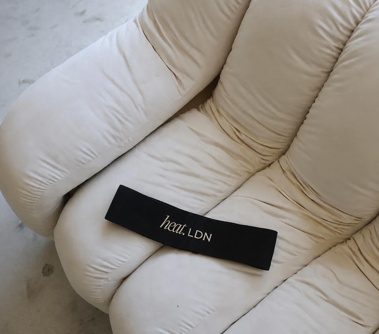 HEAT LDN branded booty band on a cream chair